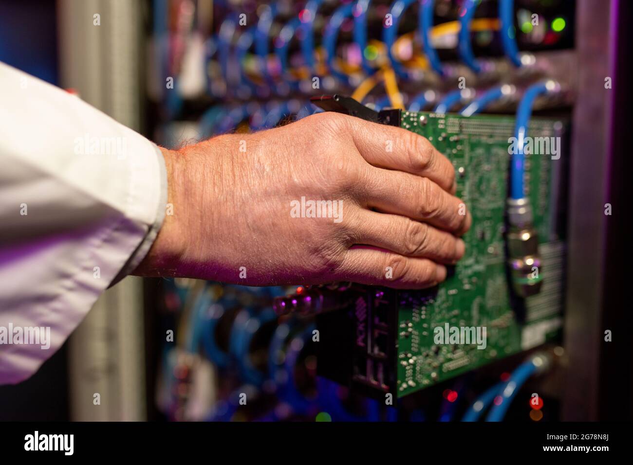 Close-up of unrecognizable server engineer installing server component into rack cabinet Stock Photo