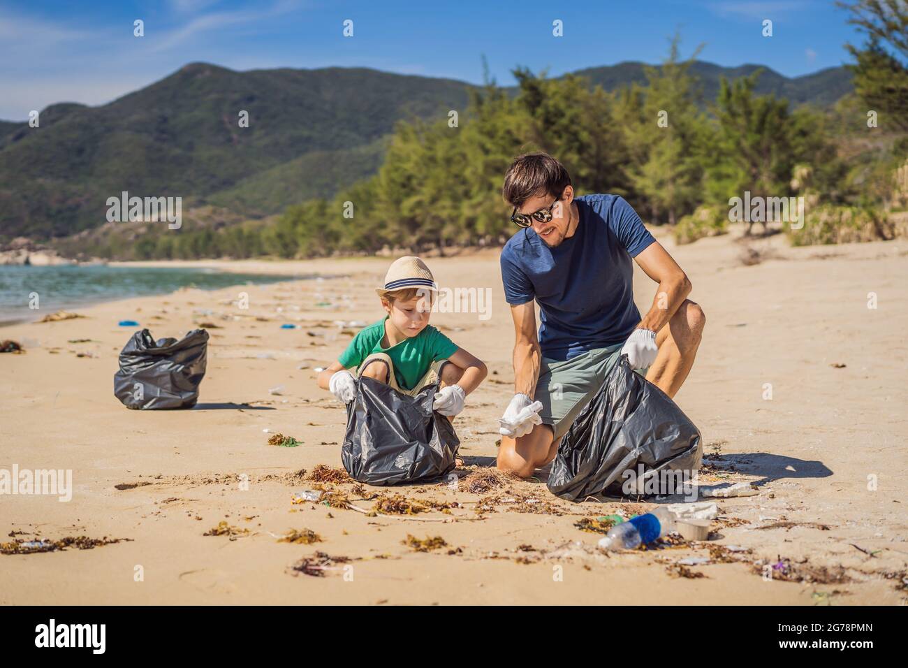 Dad and son in gloves cleaning up the beach pick up plastic bags that