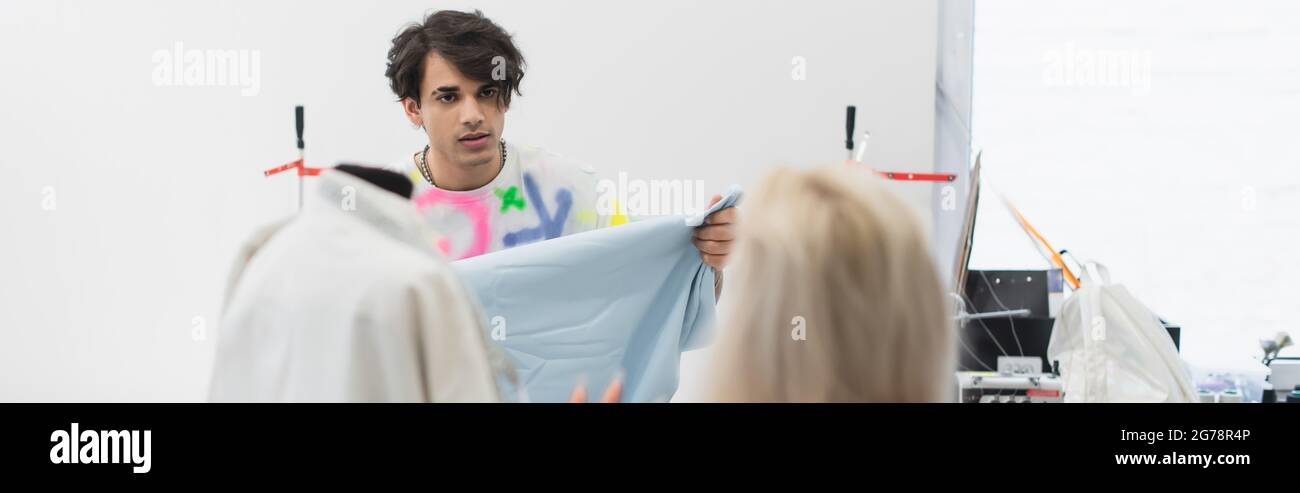 fashion designer showing sample of textile to colleague on blurred ...