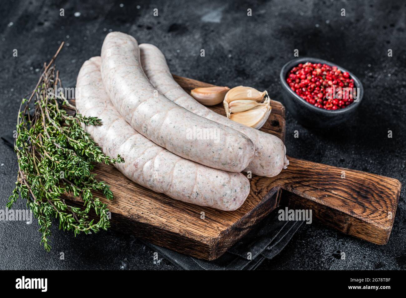 Raw Munich white sausage weisswurst on wooden board. Black background. Top view Stock Photo