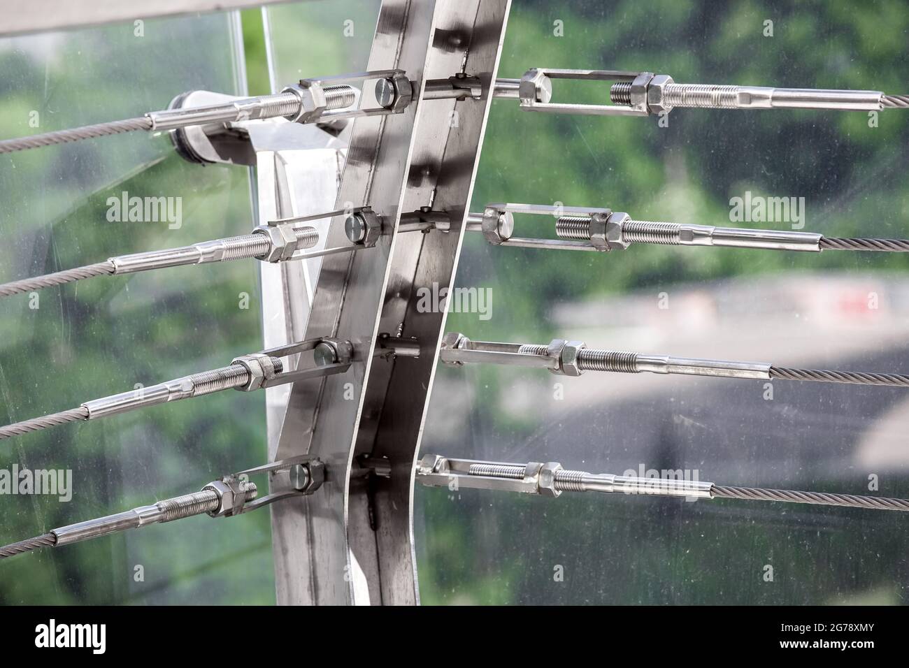 A close up view of tension steel cables with steel fasteners, a detail of frame on glass bridge with fastening engineering construction stainless stee Stock Photo