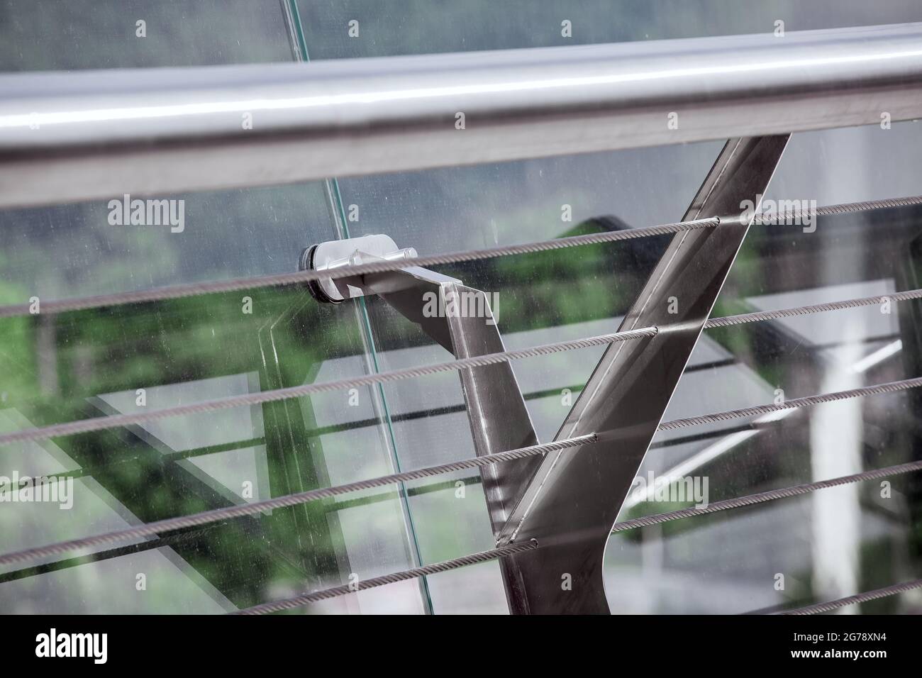 railings with glass panels fastenings enclosing the edge of the pedestrian bridge with tension steel cables for tensioning the structure close-up. Stock Photo