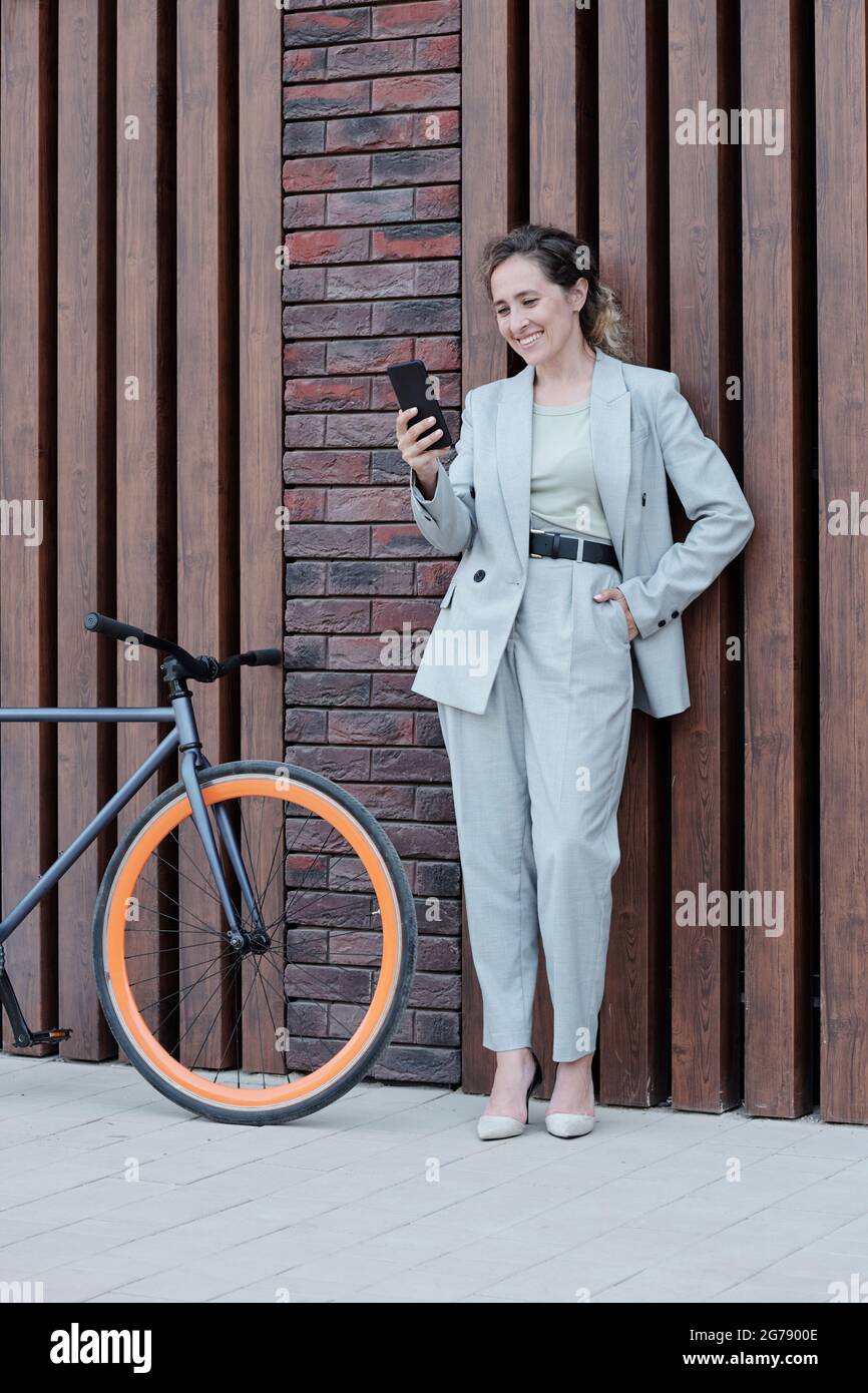 Well-dressed businesswoman with smartphone talking through video chat outdoors Stock Photo