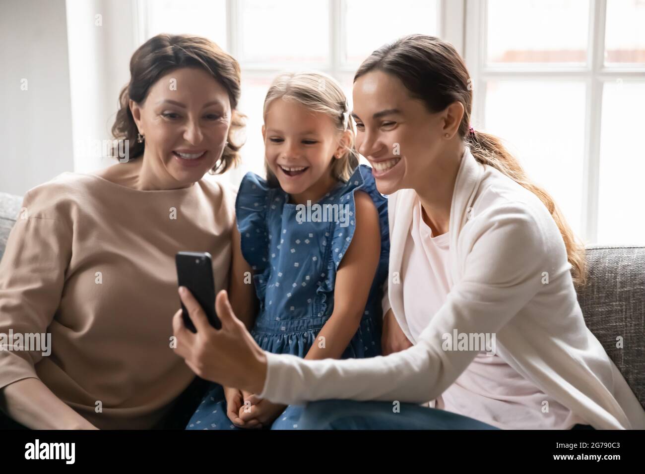 Smiling three generations of women use smartphone Stock Photo - Alamy