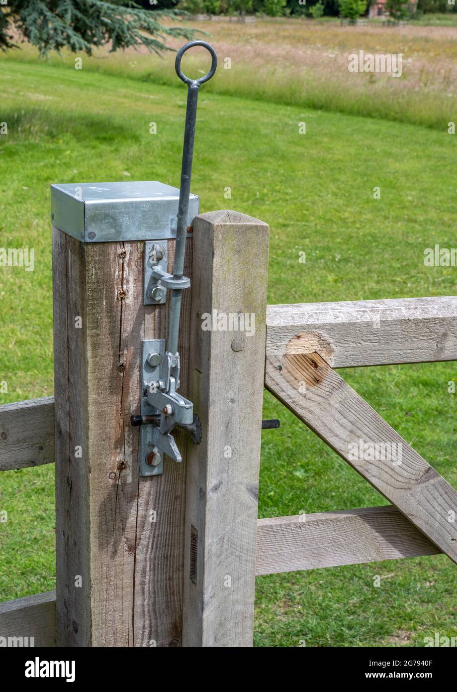 Metal gate locking mechanisim mounted on a wooden gate post with metal cap Stock Photo
