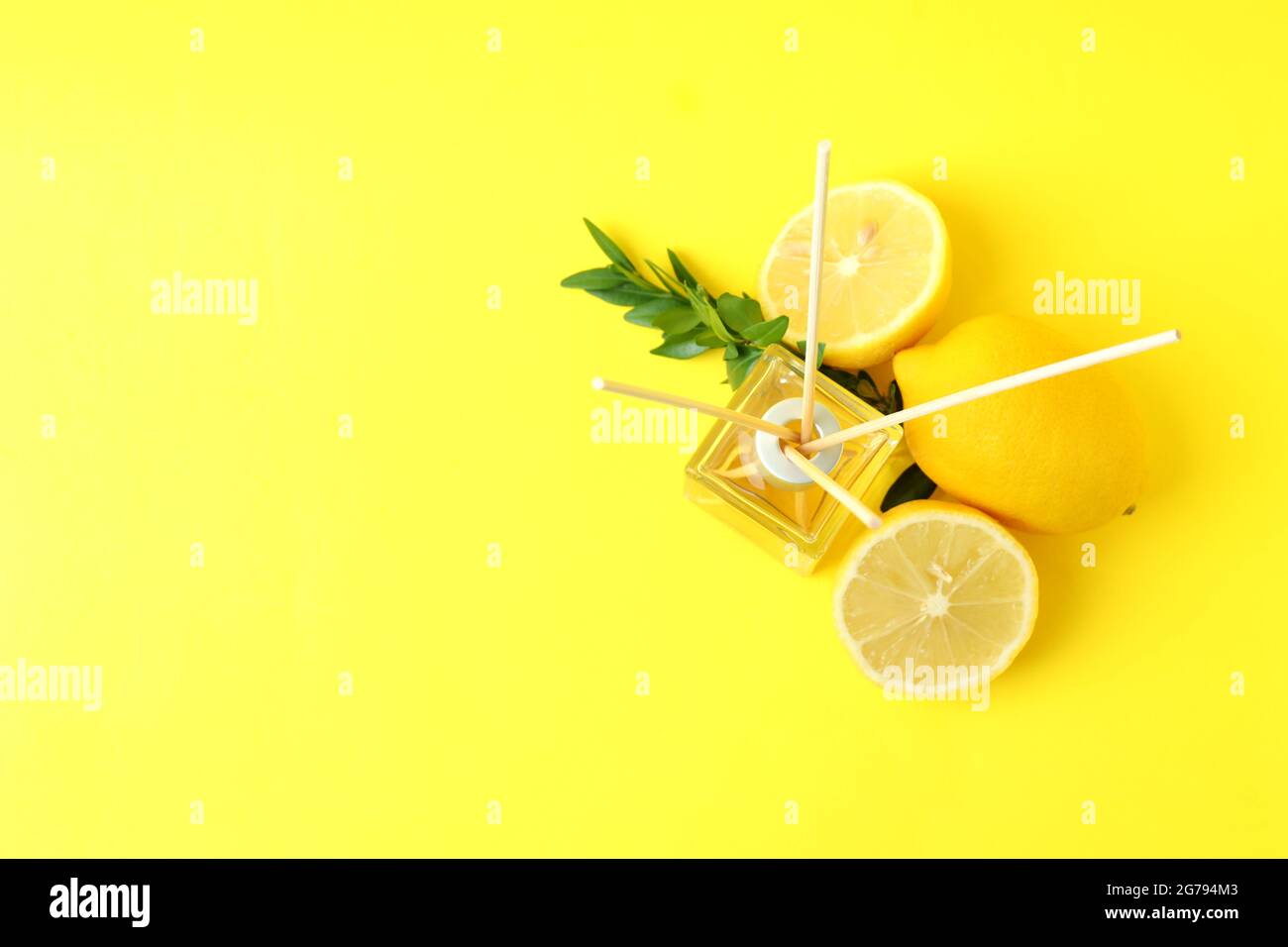Diffuser, lemons and leaves on yellow background Stock Photo