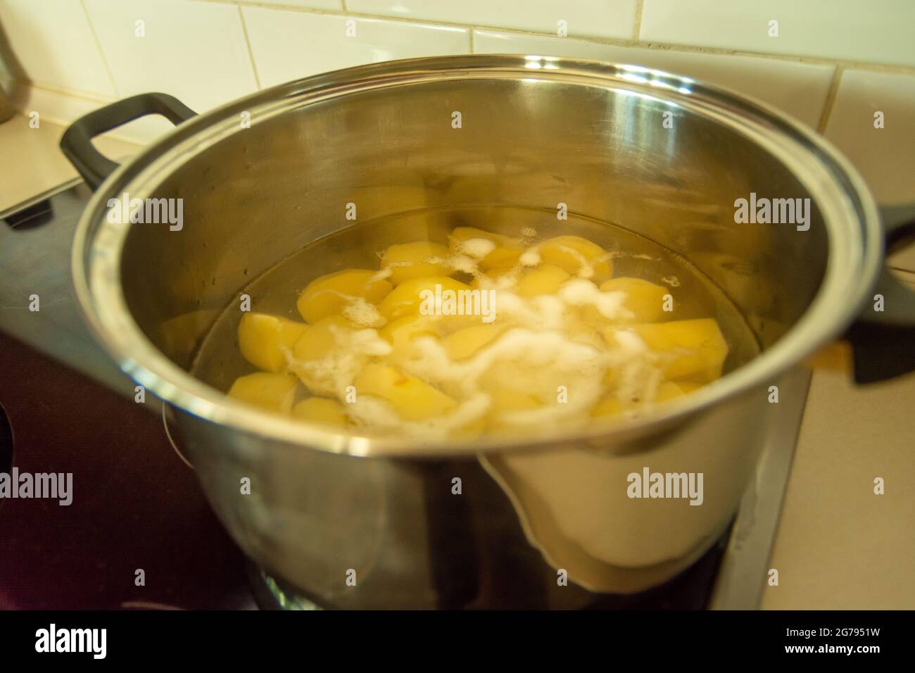 Cooking a peeled potato in water in a silver big pot Stock Photo