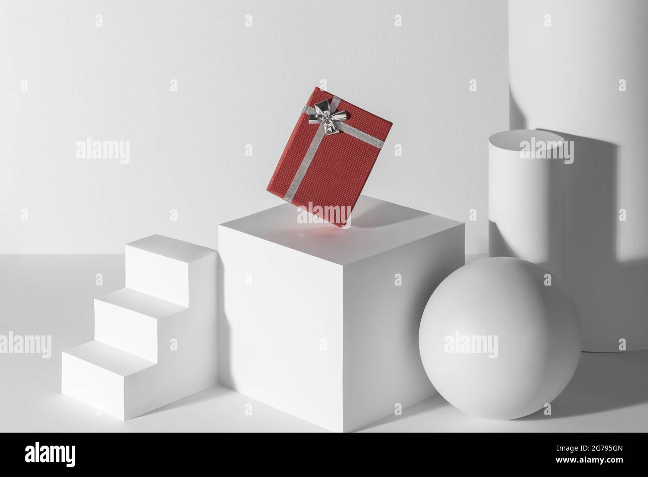 Red gift box with silver ribbon among white 3d shapes Stock Photo - Alamy