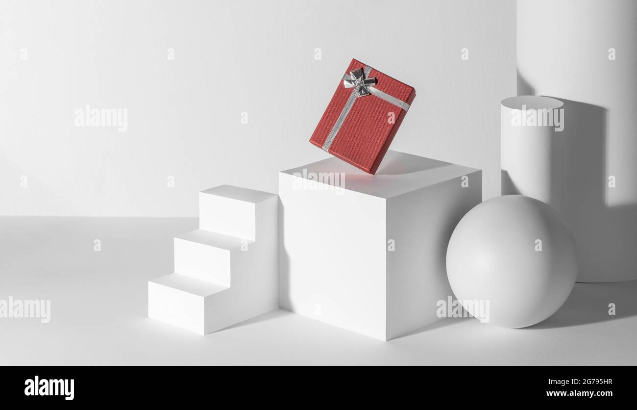 Red gift box with silver ribbon among white 3d shapes Stock Photo - Alamy