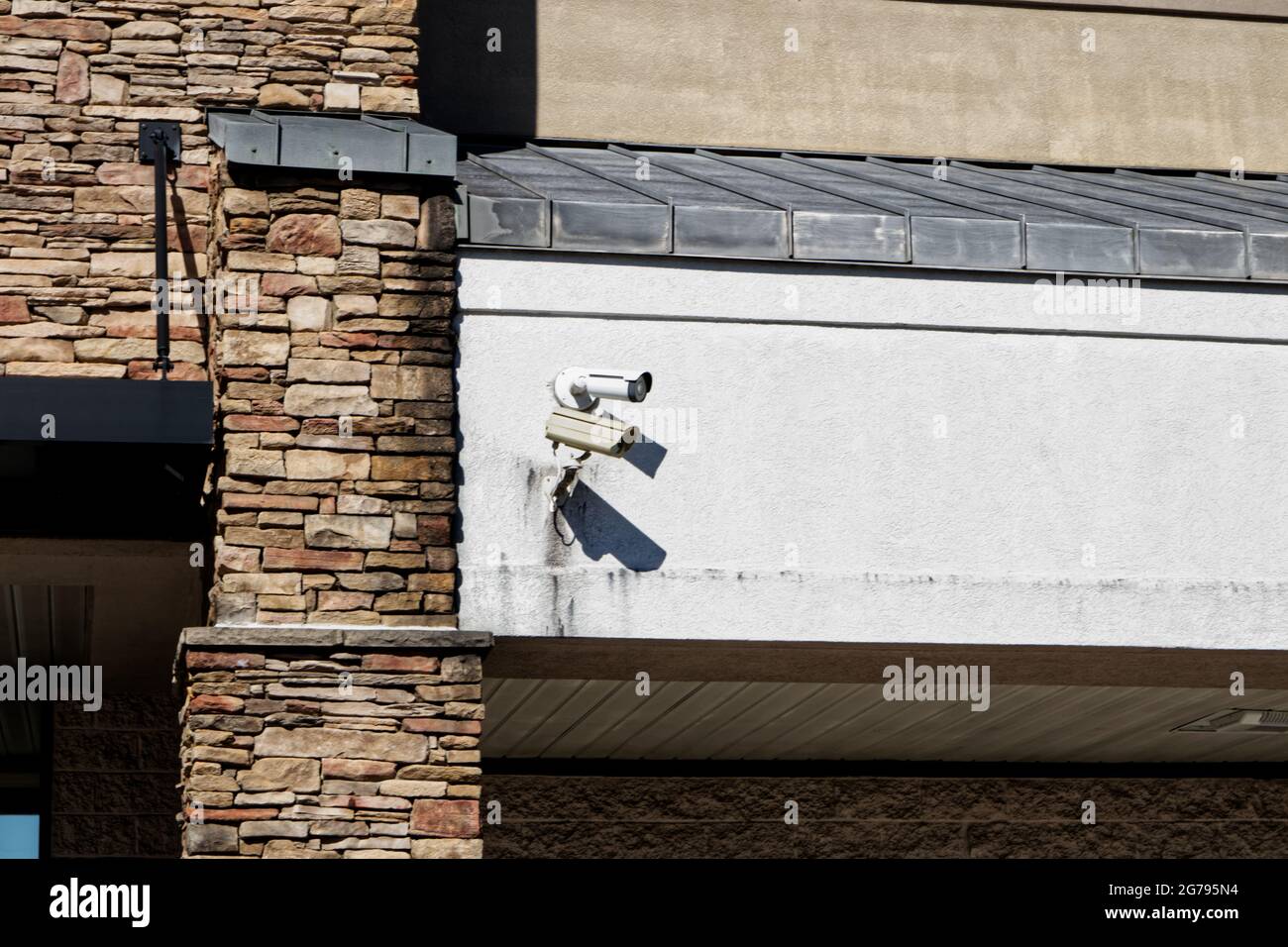 Cameras on the exterior of a building with stone texture and stucco