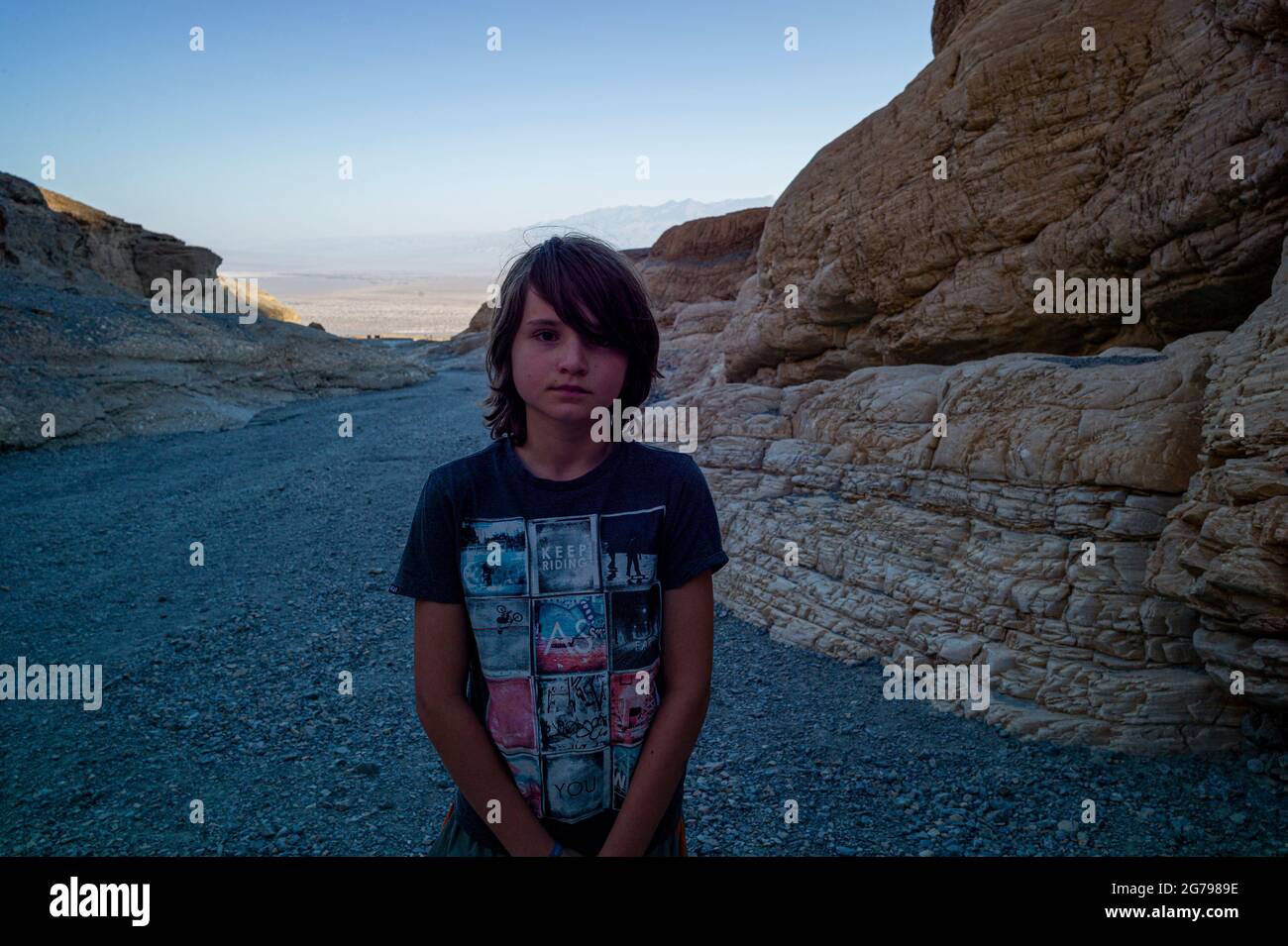 A Caucasian boy, 10-15 years posing in front of rocks in Death Valley, California, USA Stock Photo