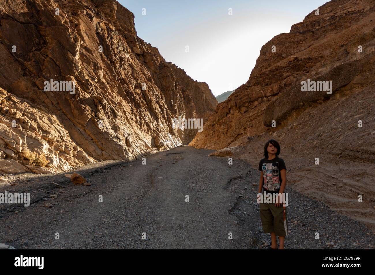 A Caucasian boy, 10-15 years posing in front of rocks in Death Valley, California, USA Stock Photo