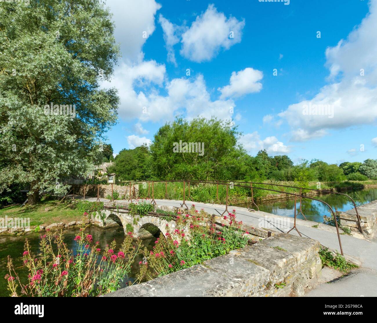 Great Britain, GL Gloucestershire, Bibury near Cirencester, bridge over the River Coln, historic stone bridge, footpath to Arlington Row. The artist and writer William Morris called Bibury 'the most beautiful village in England'. Stock Photo