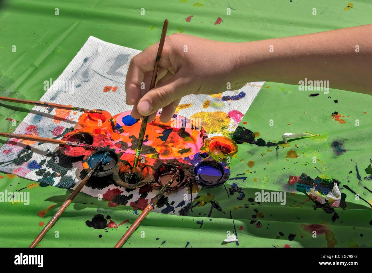 children's hand with drawing brush and paints; Stock Photo