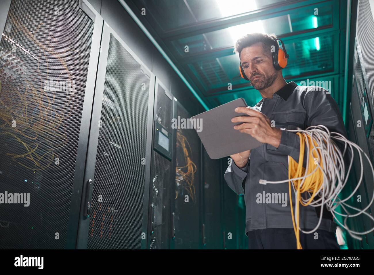Low angle portrait of network engineer using tablet in server room during maintenance work in data center, copy space Stock Photo