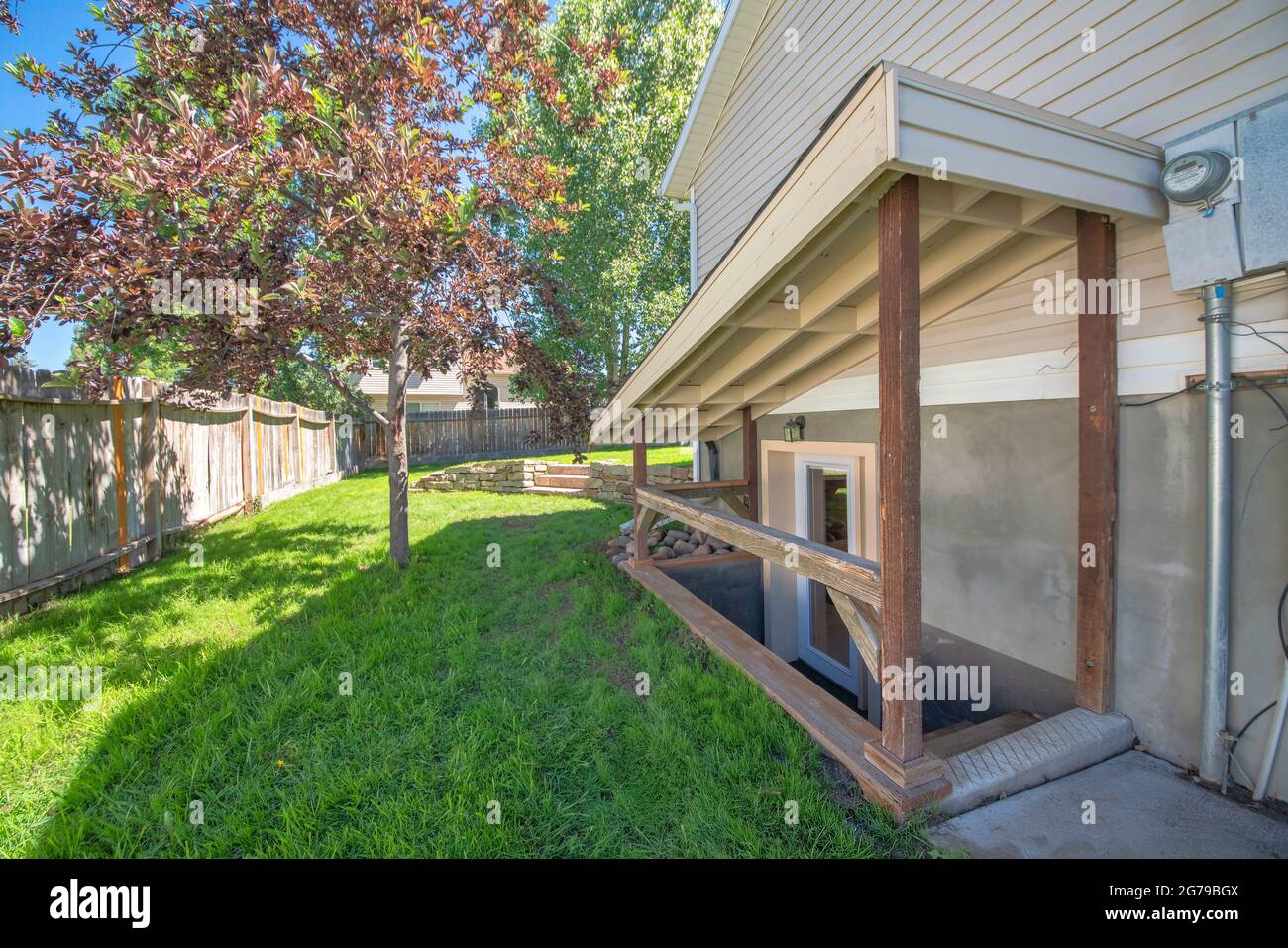 Separate basement apartment entrance with stairs, glass panel and trees