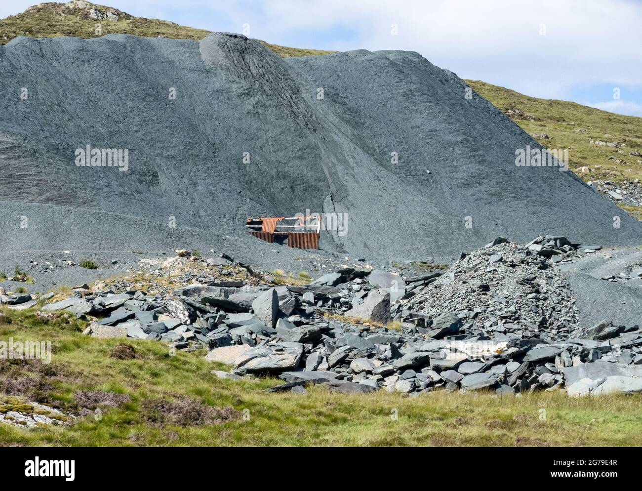 Green slate quarry in Honister Pass in the English Lake District with spoil heap burying quarry buildings - Cumberland UK Stock Photo