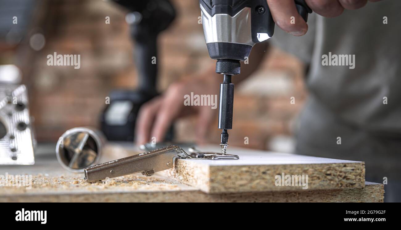 Screwing a self-tapping screw into a metal fastening hole on a wood ...