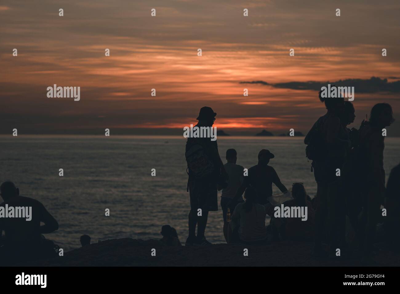 A magical place: People applaud when the sun sets at Arpoador rock with view of Ipanema beach and the Mountains of Morro Dois Irmaos and Leblon in the back. Camera: Leica M10 Stock Photo