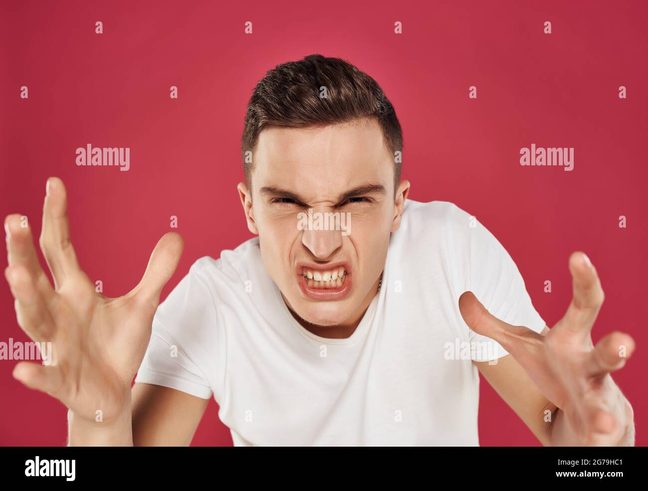 disgruntled man with an angry expression in a white t-shirt gesturing ...