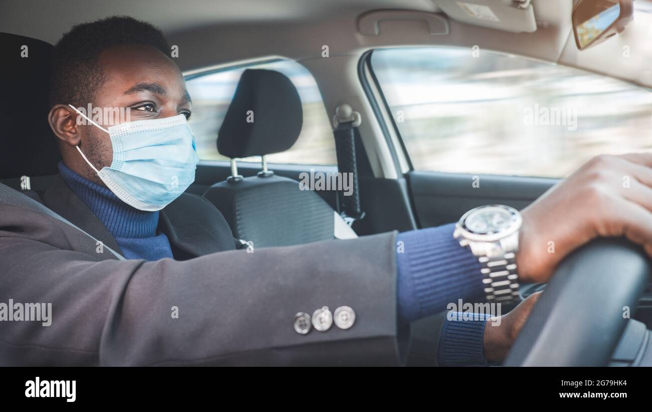 African business man driving a car with wearing medical mask for protection corona virus or Covid-19 Stock Photo