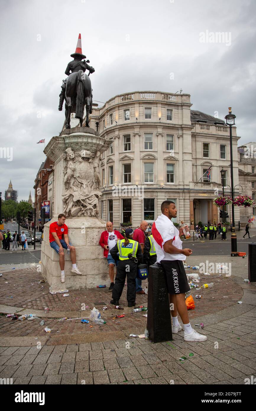 Euro 2020 Final England vs. Italy --- Football fans and police by an equestrian statue of Charles I sporting a traffic cone for the occasion. Stock Photo
