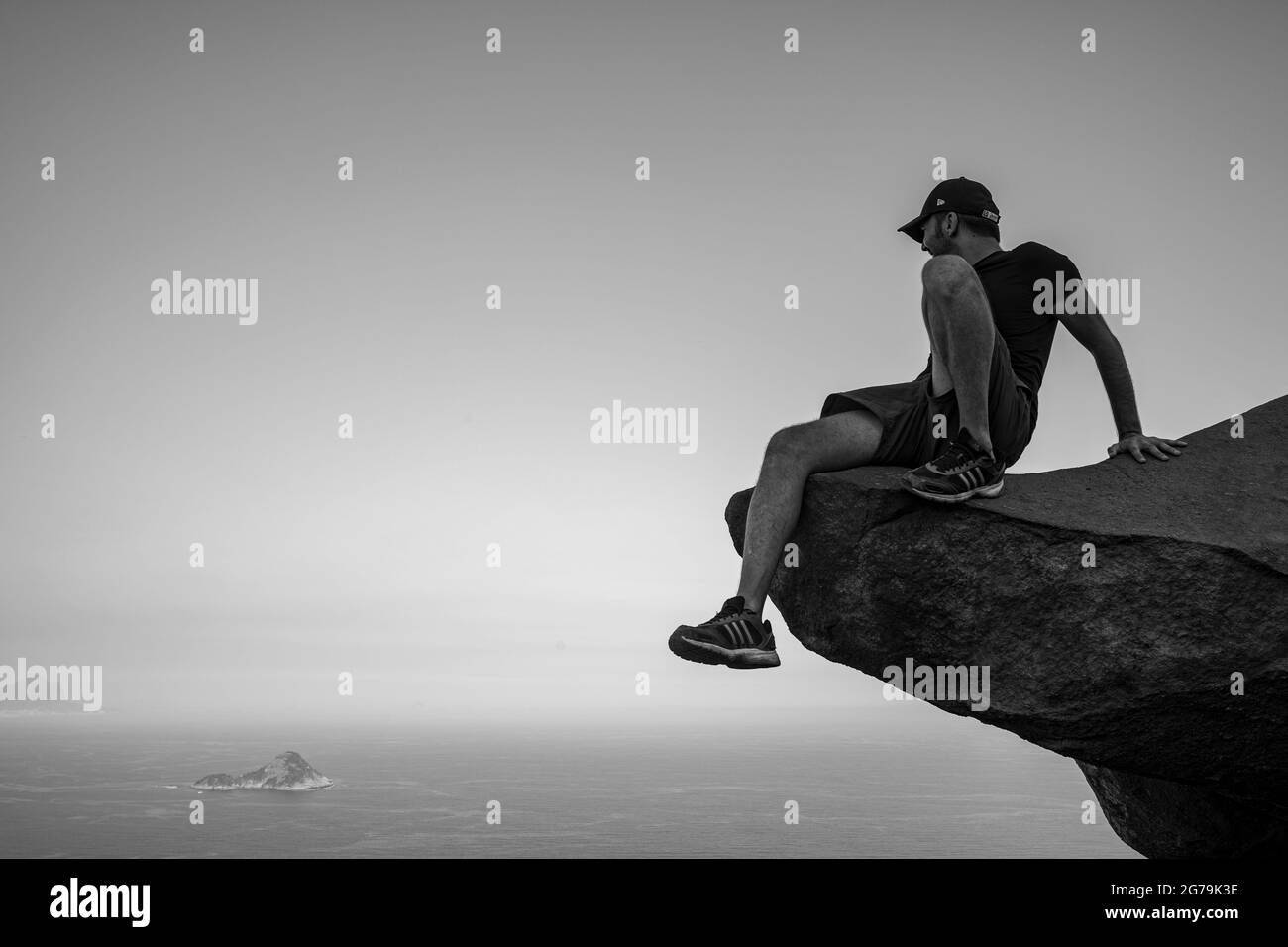 A man enjoying the view to the wild beaches from a rock on the top of the Pedra do Telegrafo mountain, Barra de Guaratiba, Rio de Janeiro, Brazil. Shot with Leica M10 Stock Photo