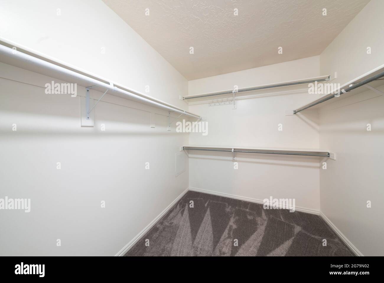 White empty walk in closet with carpeted floor and shelves with metal ...