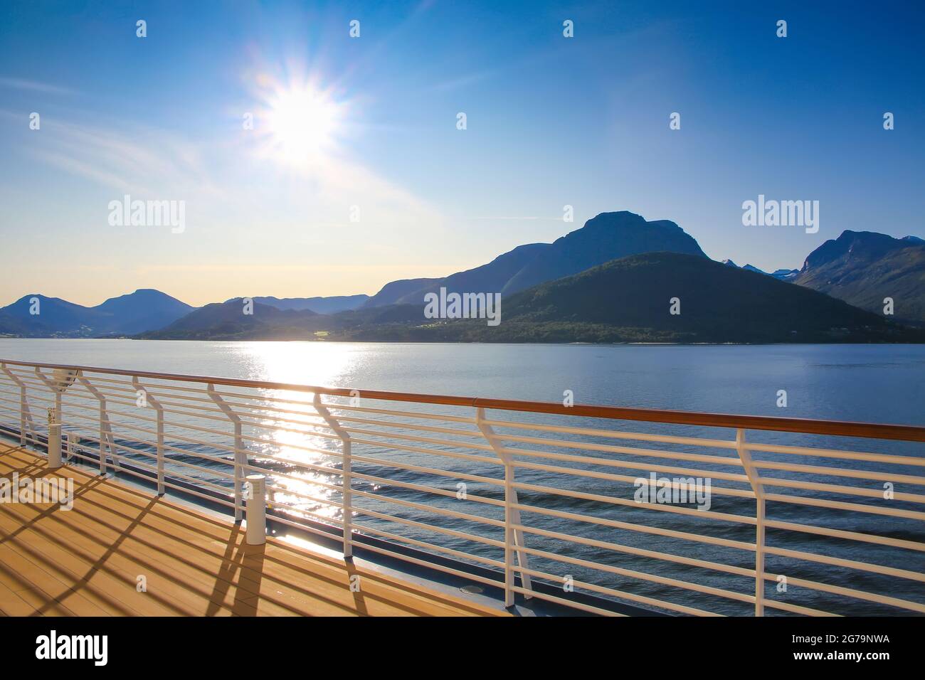 Cruise towards Geiranger fjord on a beautiful day with views of the Norweigan mountains from the open promenade deck of the ship, Norway. Sunset over Stock Photo