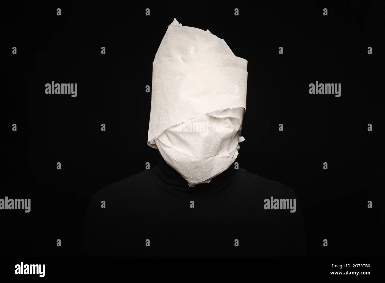 Head wrapped in toilet paper. Funny man, black background. Mummy, stupid dummy, mental health concept. Stock Photo