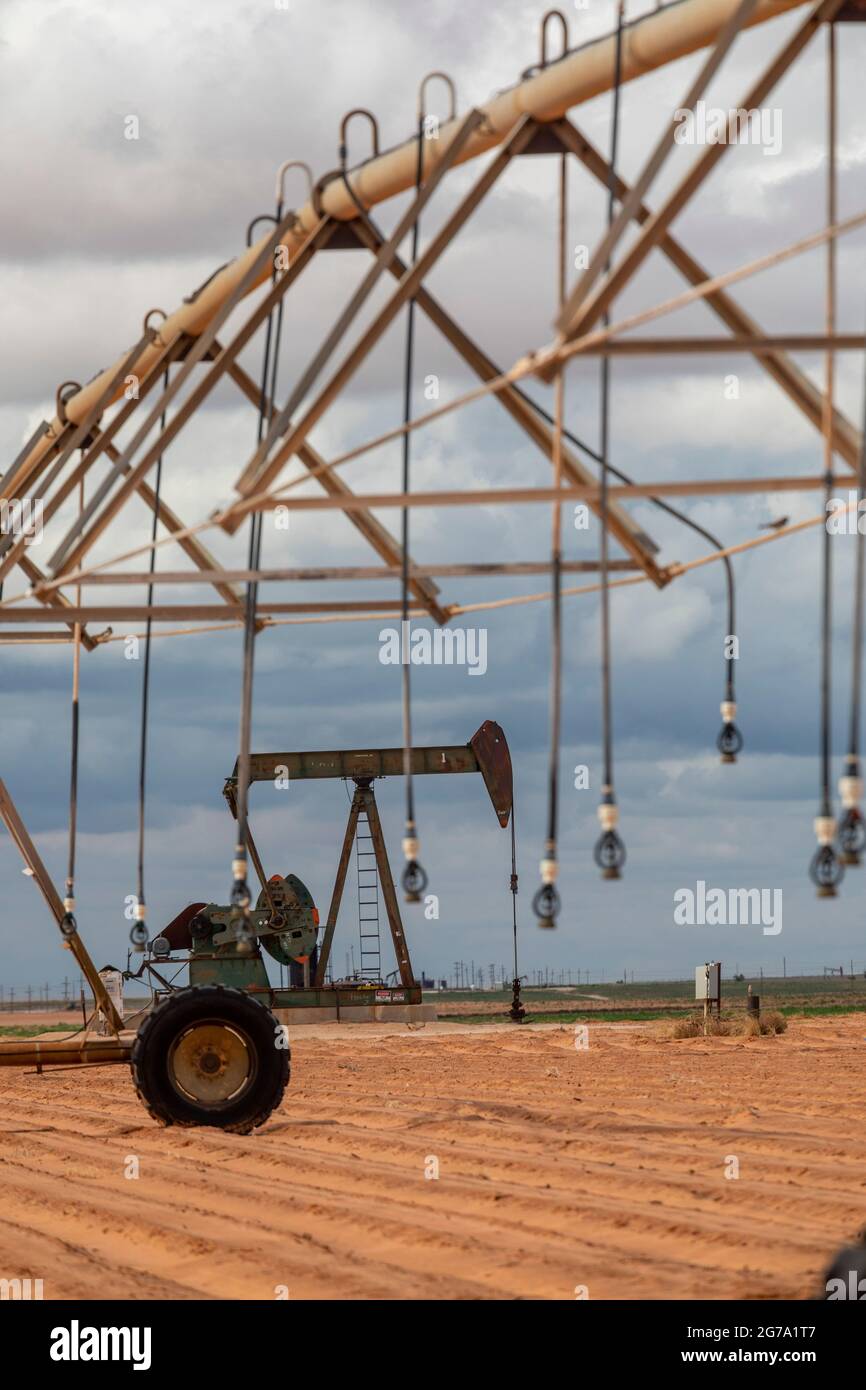 Plains, Texas - An oil well near irrigation equipment on farm land in the Permian Basin. Stock Photo