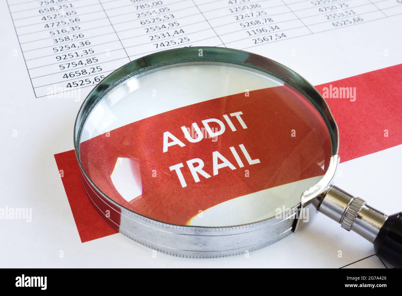 Audit trail report and magnifying glass on the page. Stock Photo