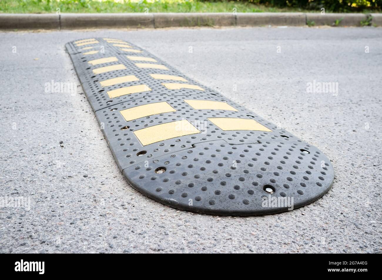 Yellow and black speed bumps on the asphalt road. Obstacle in the path