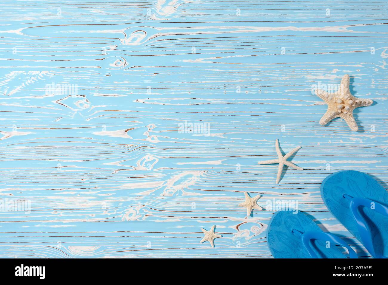 Sea stars and rubber beach blue flip flops on blue wooden background Stock Photo