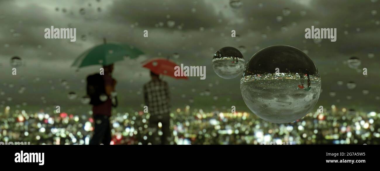 Two people looking over a city at night with umbrellas in a rain storm ...