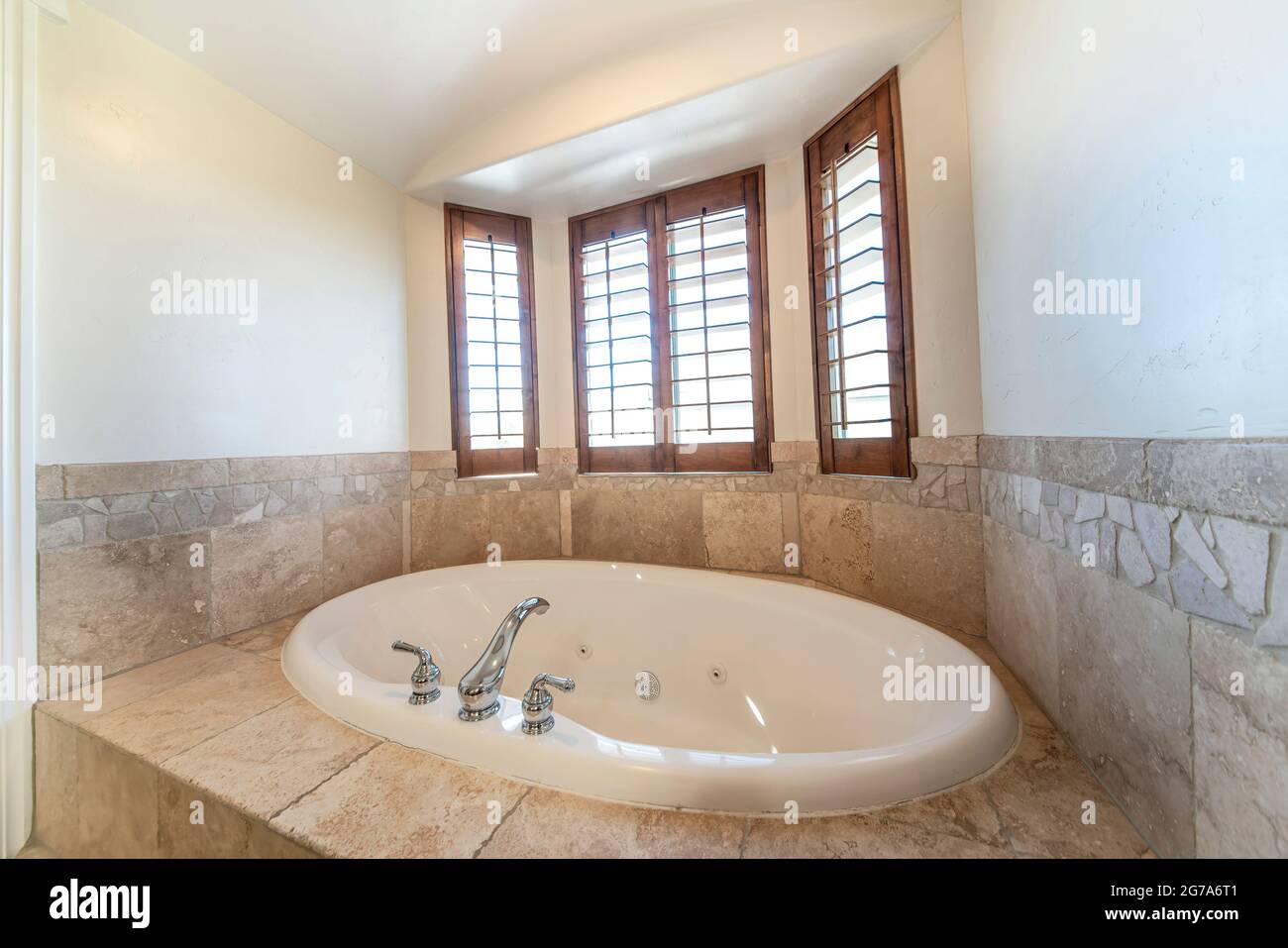 Drop in bathtub with rough marble tile surround and deck Stock Photo