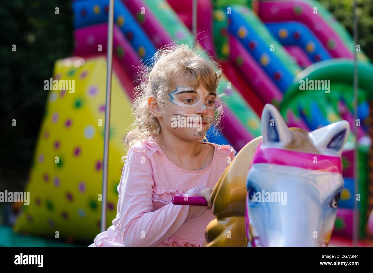 girl with face-painting of cat in marry-go-round Stock Photo