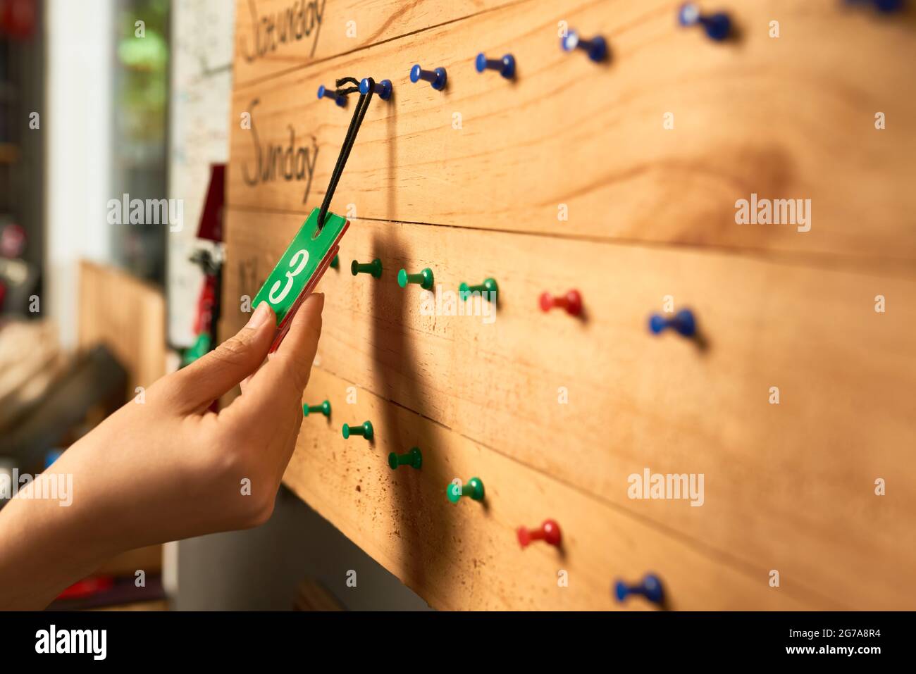 Hands of female workshop worker hanging plastic plate with number on wooden board Stock Photo
