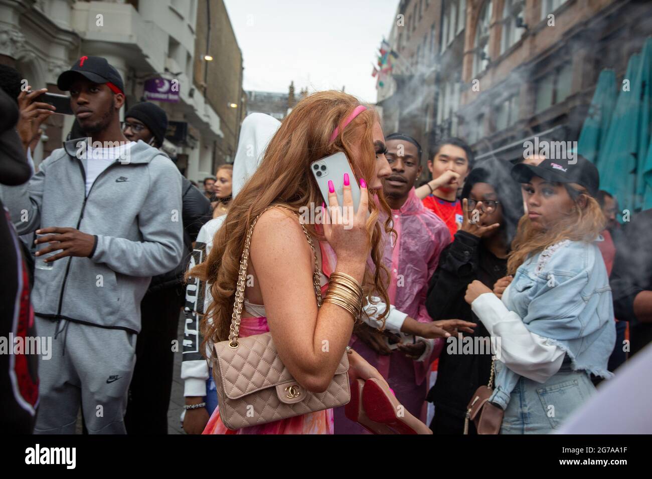 A young traveller woman with pink nails walks along Leicester Square ahead of the Euro 2020 Final England vs. Italy. Stock Photo