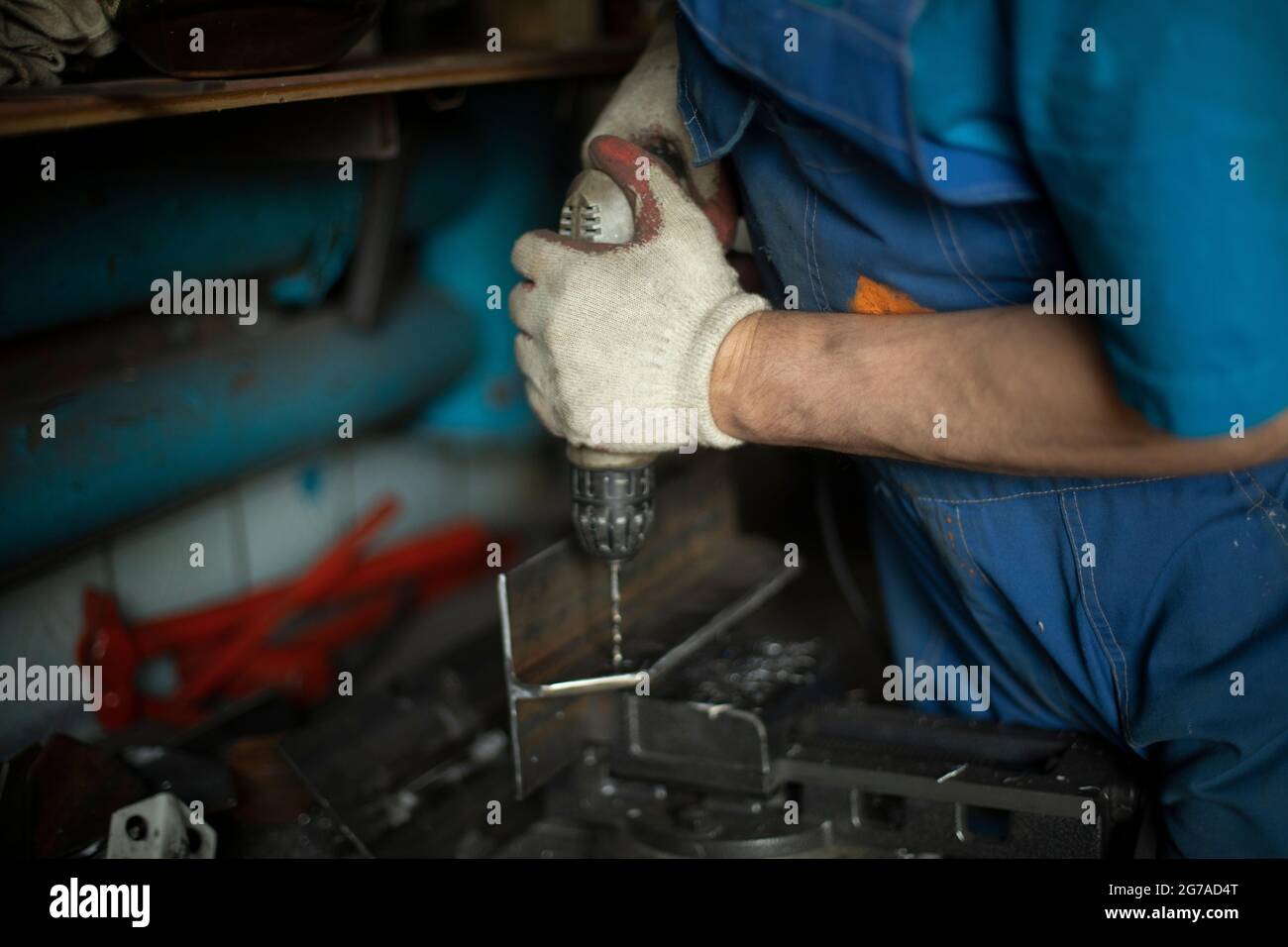 Drills metal with a drill. The man is working. Drilling holes in steel. Work in a metal