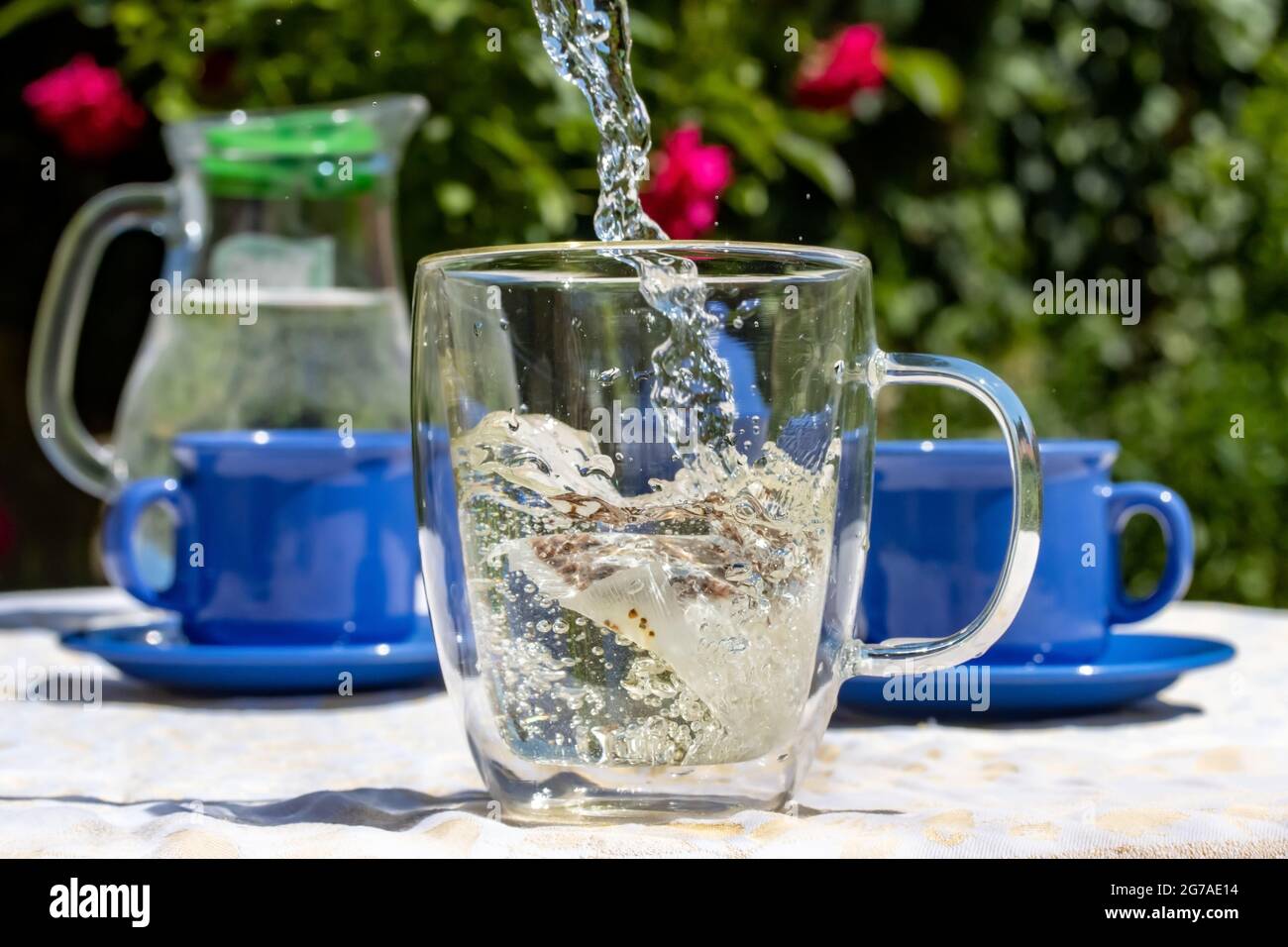 https://c8.alamy.com/comp/2G7AE14/water-flows-into-a-mug-with-a-tea-bag-a-picnic-in-the-summer-garden-2G7AE14.jpg