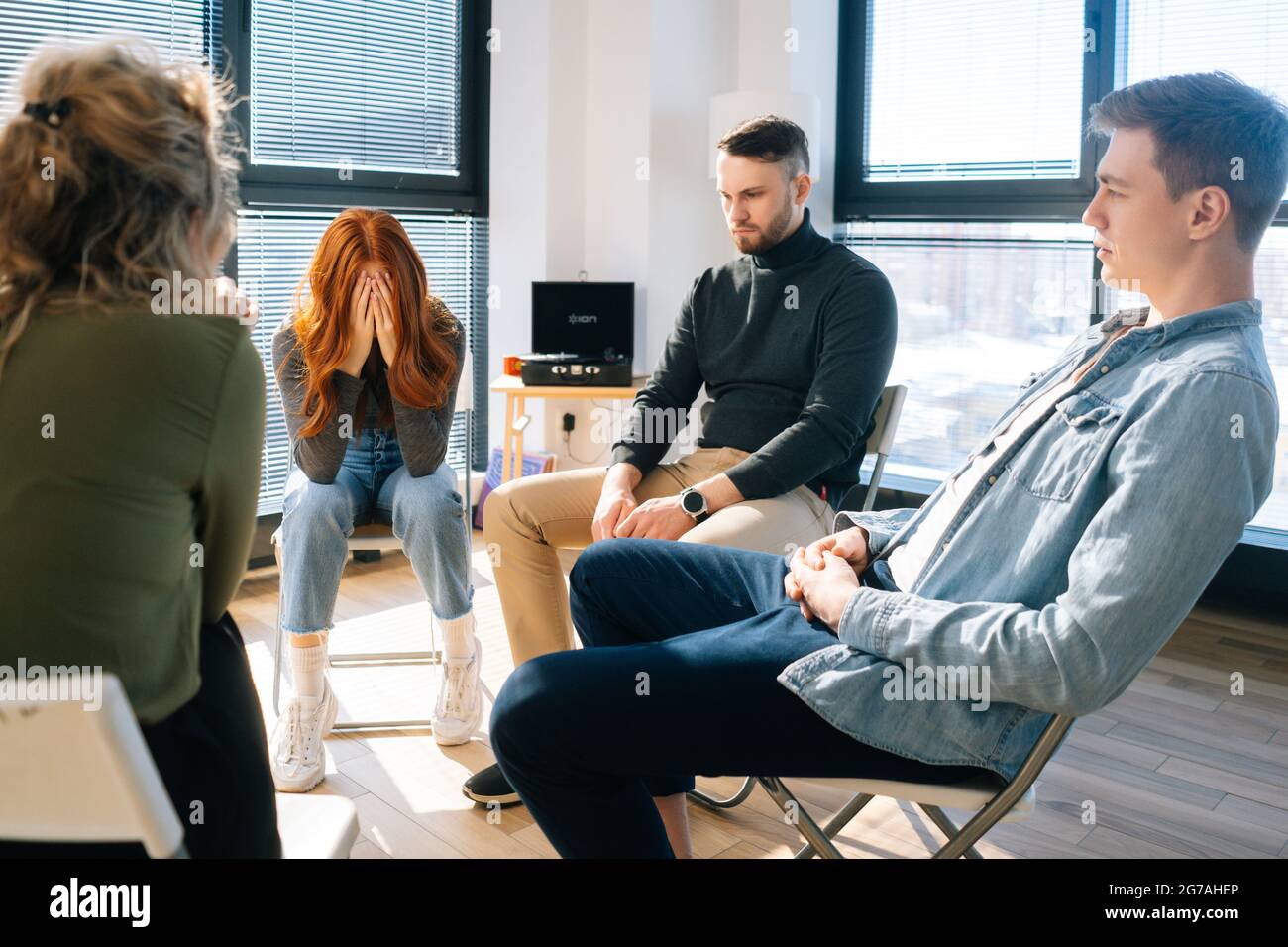 Front view of sad frustrated young woman sharing problem during group