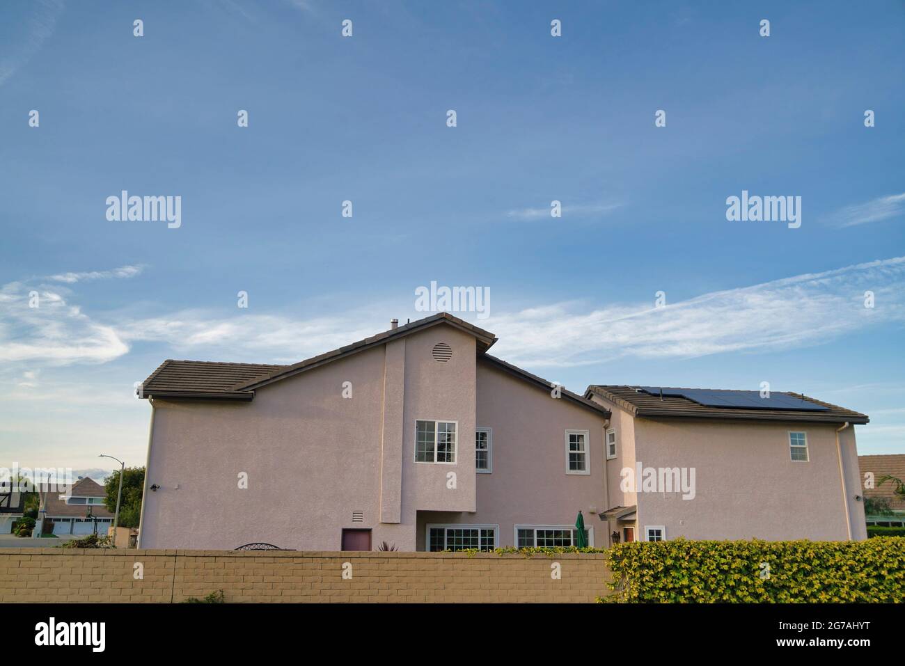 Two storey house exterior with beige wall and solar panels on the pitched roof Stock Photo