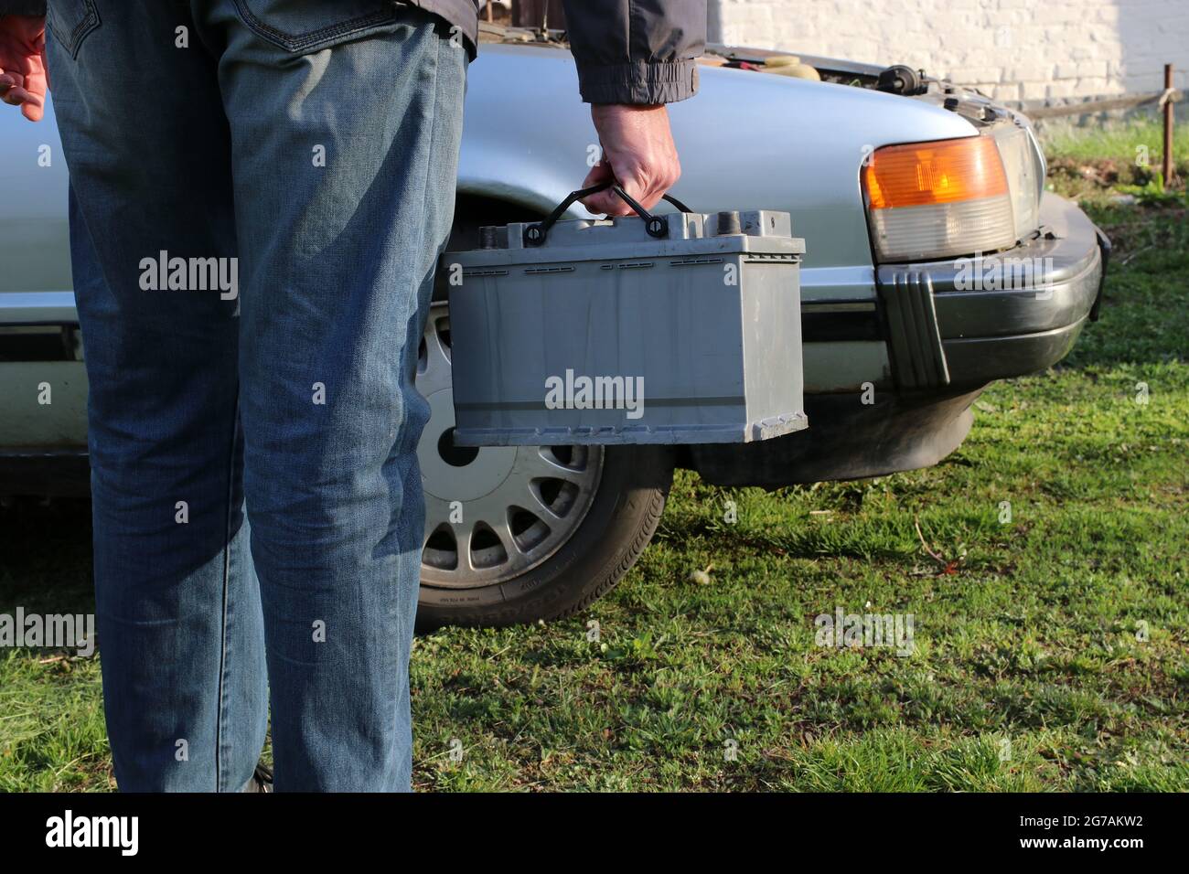 A woman carries a car battery for installation in a car. Stock Photo