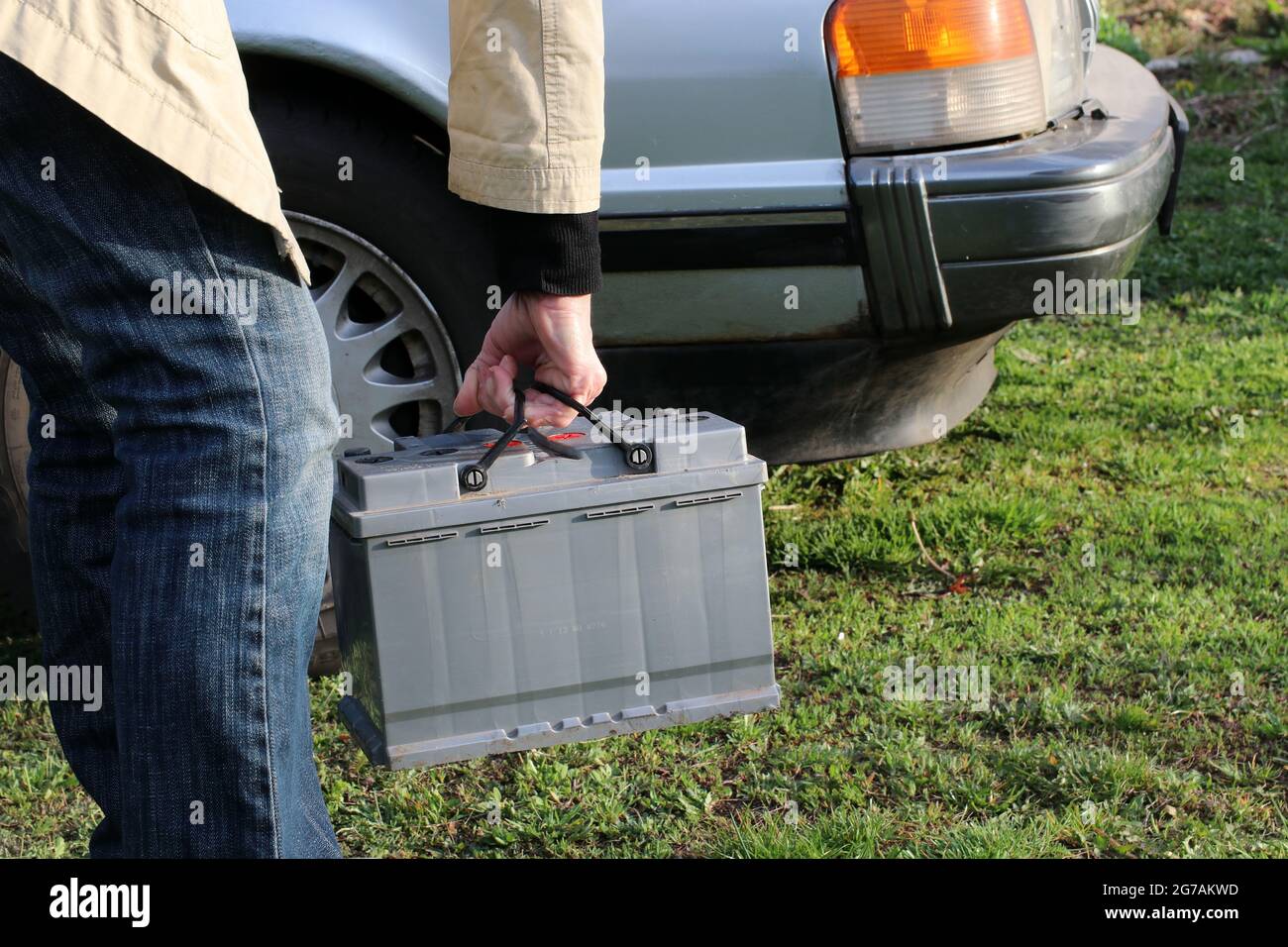 A woman carries a car battery for installation in a car. Stock Photo
