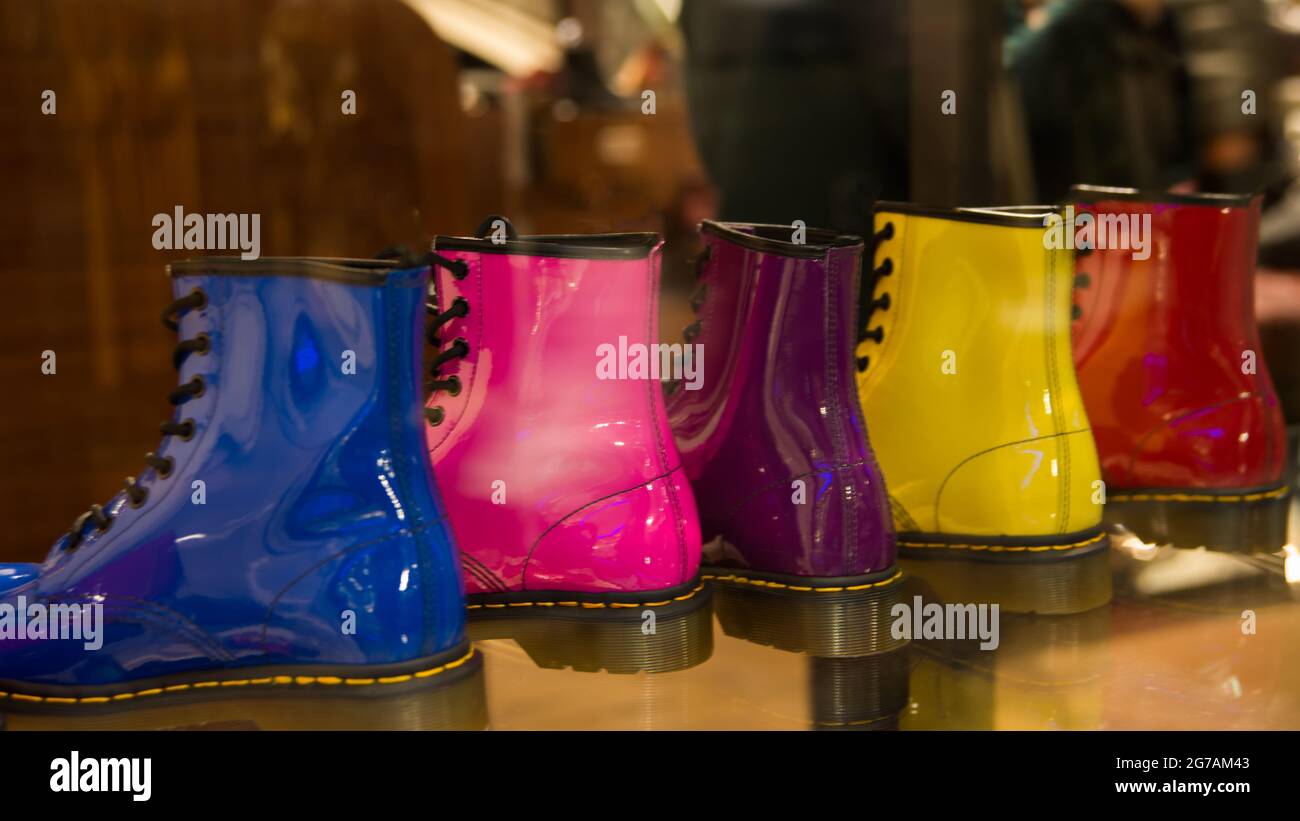 Five shining boots in a row in a storefront. Same model, five different