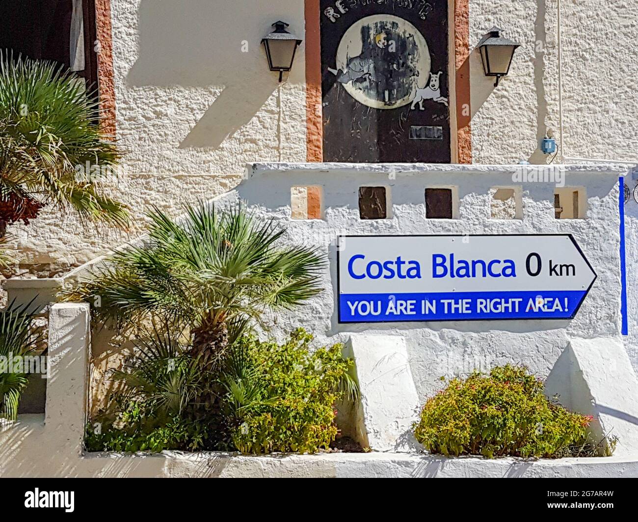 Calpe, Alicante, Spain - August 24 2016; Humorous sign advising distance of ) to Costa Blanca in coasta town Calpe, Alicante, Spain on exterior of bui Stock Photo