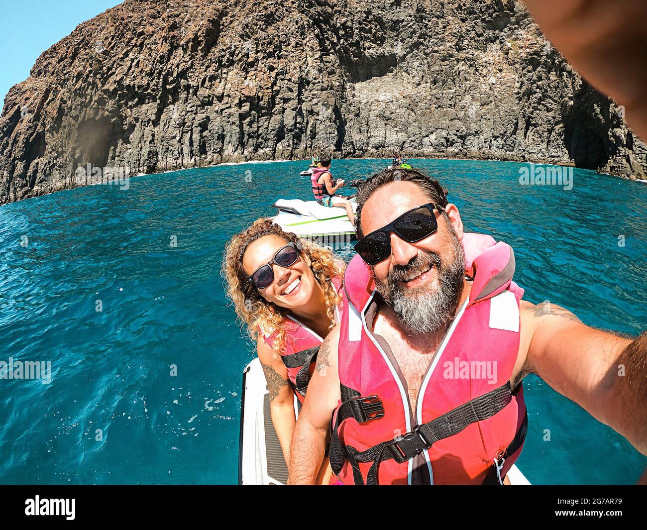 Cheerful pretty man and woman together on a jet sky having fun in summer holiday vacation - travel and happy lifestyle young people - selfie picture and smiles - blue ocean and coastline Stock Photo