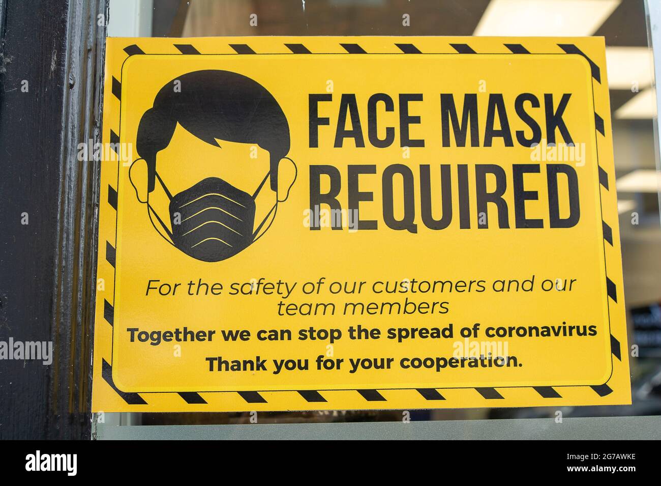 Wokingham, Berkshire, UK. 12th July, 2021. A bright Face Mask Required sign in a shop window. Wokingham has recorded another 61 positive Covid-19 cases in the past 24 hours. Boris Johnson has today announced the lifting of the Covid-19 lockdown from 19th July 2021, despite the number of positive cases spiralling out of control. Credit: Maureen McLean/Alamy Stock Photo
