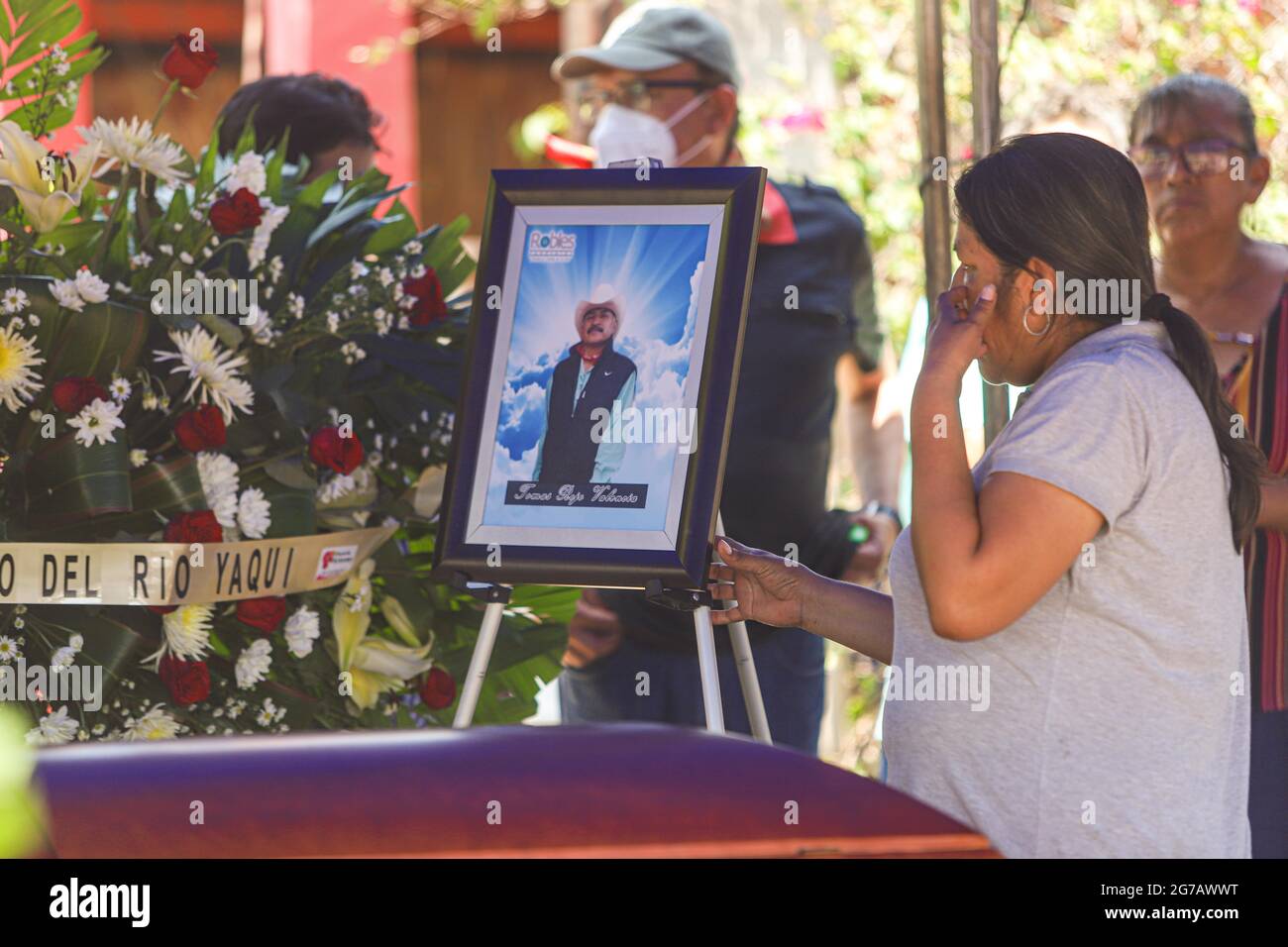 VICAM, MEXICO 10 JULIO 2021: Una mujer observa un cuadro con la fotografia  de Tomas Rojo a un costado del ataud, durante la ceremonia funebre para  despedir a Tomas Rojo activista y